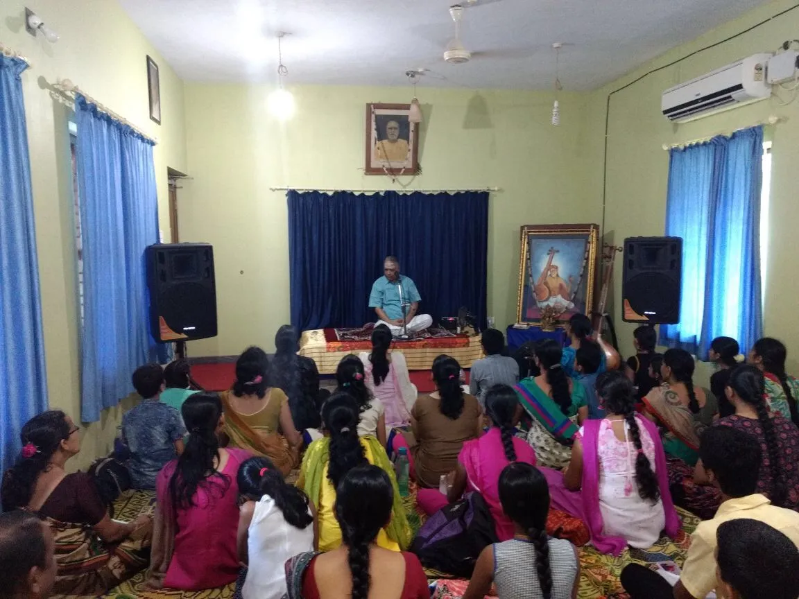 The Ganamadhuryam orientation camp in progress: the visiting vidwan seated on the platform with students cross-legged on the floor of the Narayaneeyam hall before him.