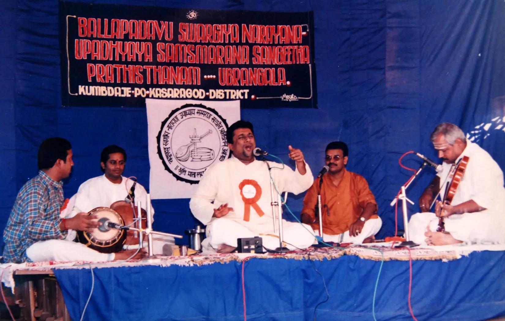 Vidwan Sanjay Subrahmanyam’s Sangeetha Aradhana concert in 2004, the ensemble seated on a white sheet beneath the trust’s blue banner.