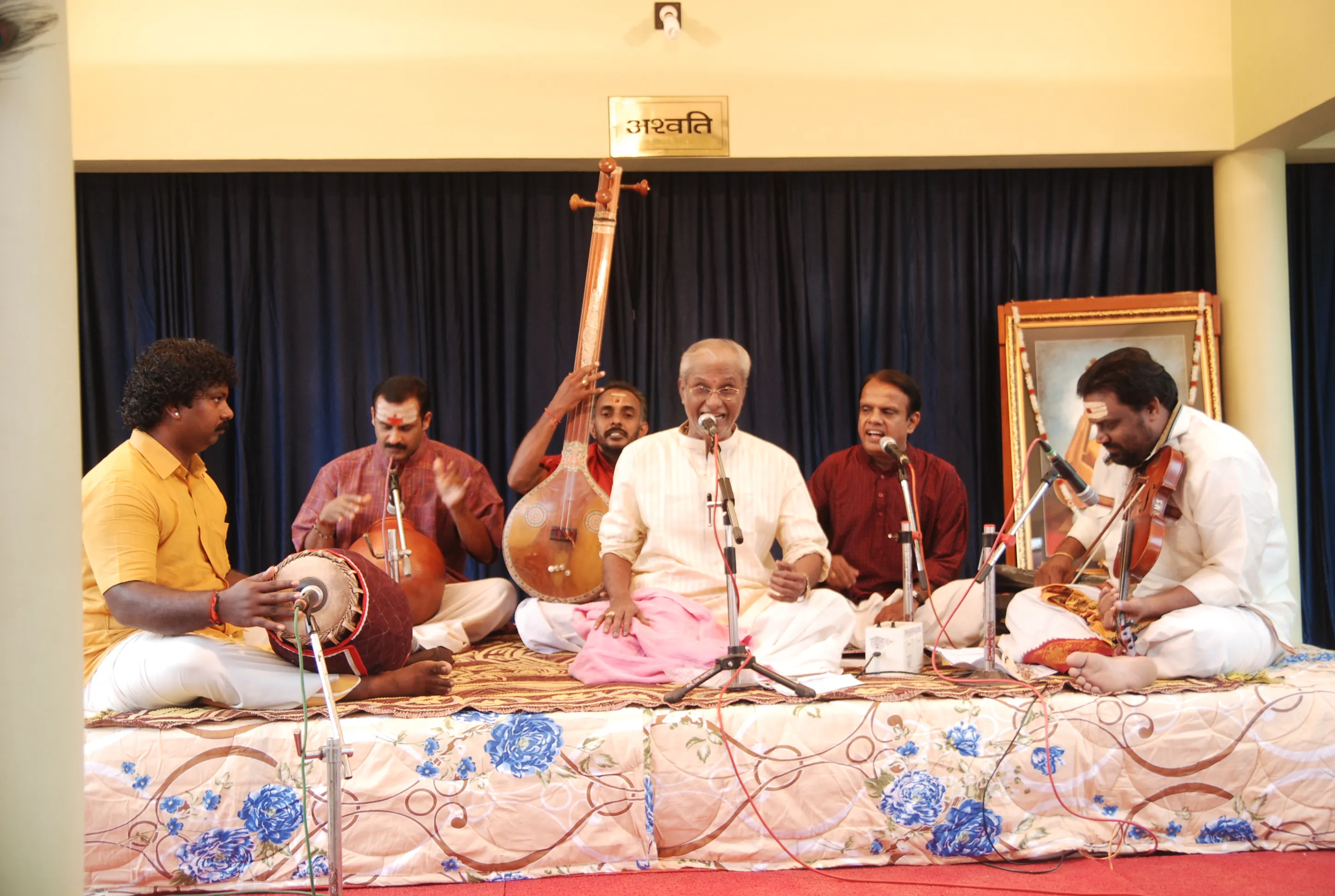A Carnatic ensemble on stage at the 2012 Sangeethothsavam — the vocalist at the microphone with tambura, mridangam, ghatam and violin players seated around him.